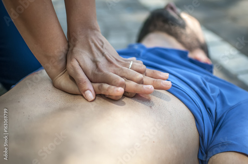 rianimazione cardiopolmonare con massaggio cardiaco su giovane svenuto a seguito di arresto cardiaco in un parco
 photo