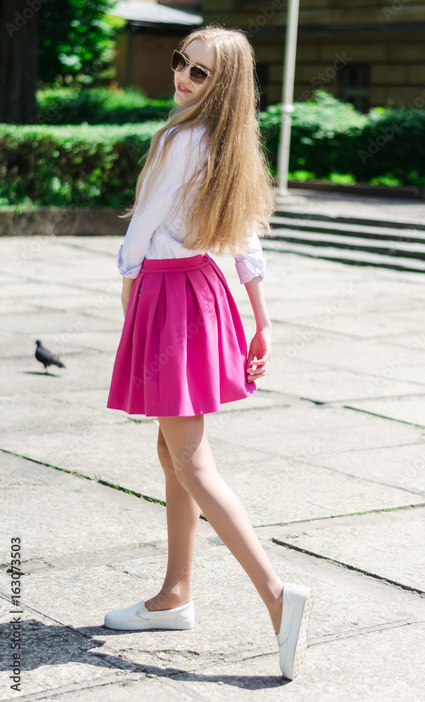 Outdoor summer portrait of a young attractive lady walking in the park