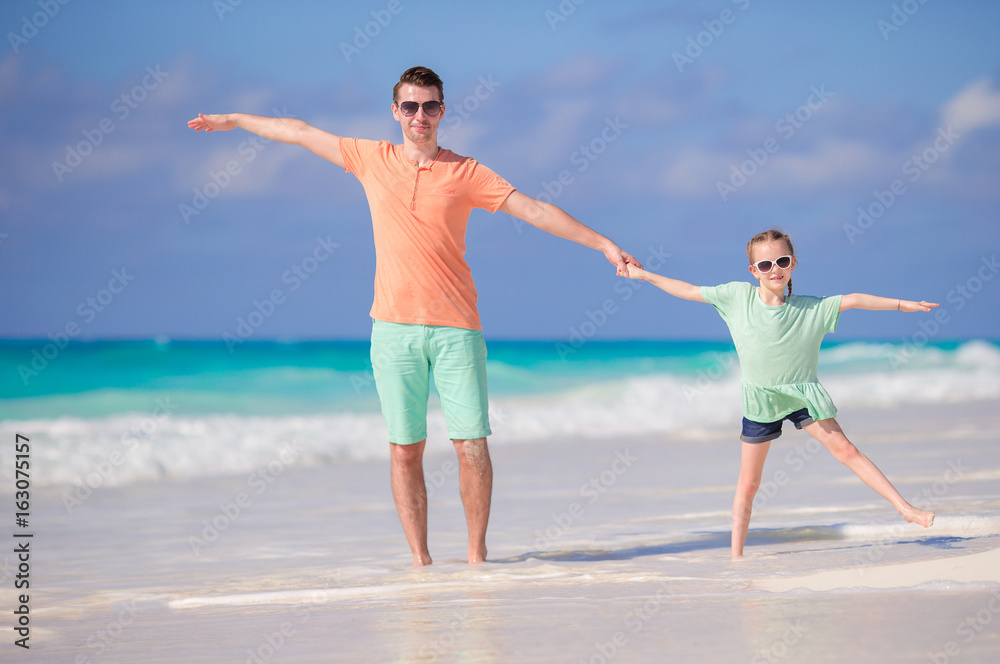 Little girl and happy dad having fun during beach vacation Little girl and happy dad having fun during beach vacation