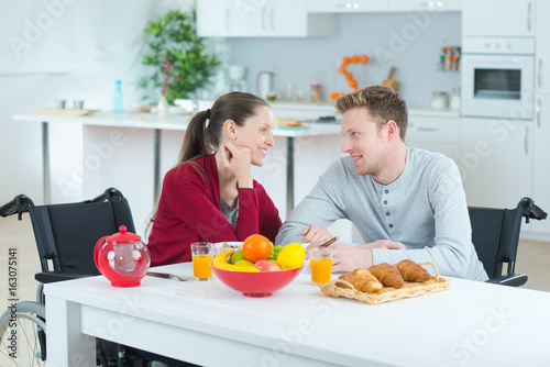 couple on a wheelchair eating the common meal indoors
