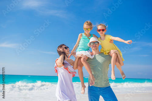 Portrait of happy beautiful family of four on a tropical beach on Carribean vacation