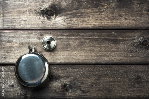 Metall round flask with cup on wooden backdrop