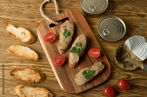 Liver pate on the bread on wooden tray.