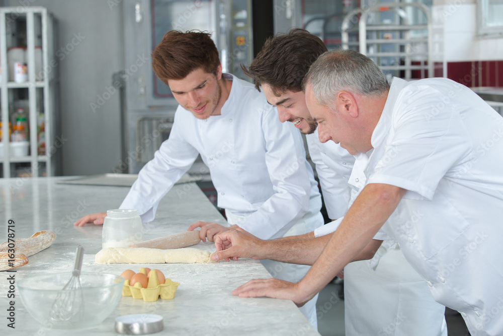 team of bakers kneading dough in a commercial kitchen team of bakers kneading dough in a commercial kitchen