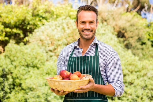 Portrait of smiling handsome man holding apple basket