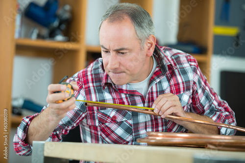 tradesman using a tool to shape a cooper tube