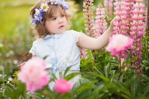 happy toddler girl with a flower wreath in the garden
