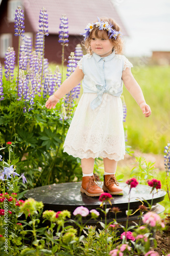 happy toddler girl with a flower wreath in the garden © Alinsa