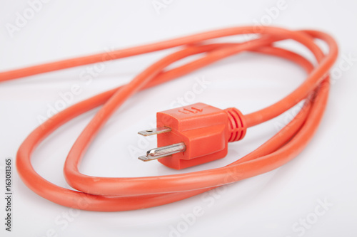 Bright orange extension cord on a white surface. Orange extension cable isolated on white background. photo