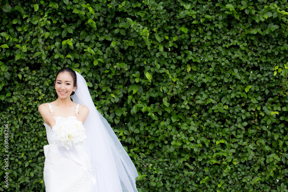 beautiful young woman on wedding day in white dress in the tree wall. Female portrait in the park - Selective focus