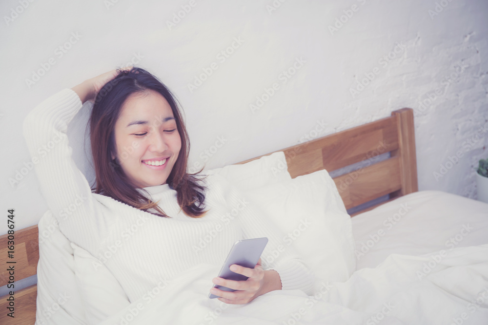 woman asian model holding a mobile phone with wake up in bedroom. woman asian model holding a mobile phone with wake up in bedroom.