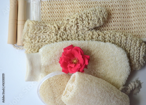 Top close up view of a set of body massage brushes for dry brushing, exfoliation and lymph drainage with a red rose on white 