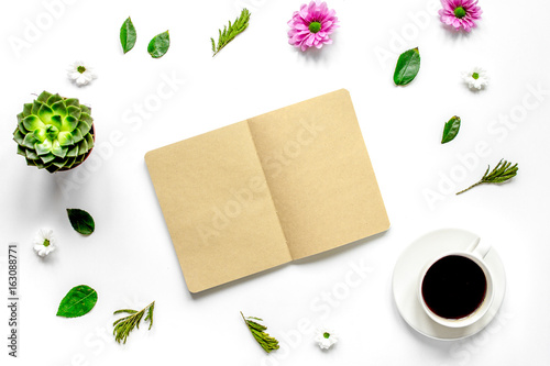 Coffee cup with flower petals and notebook top view mock-up