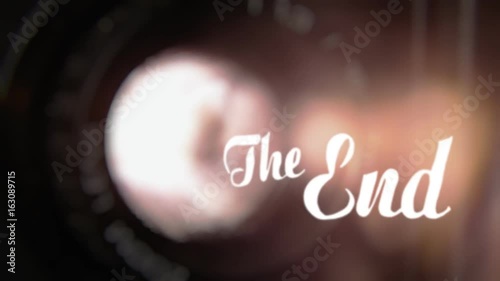 Animation of a retro vintage old fashioned The End title, silent film ariston style, slowly appearing, over the lens and the light beam from a fancy Super 8 mm projector. Diegetic audio.
 photo