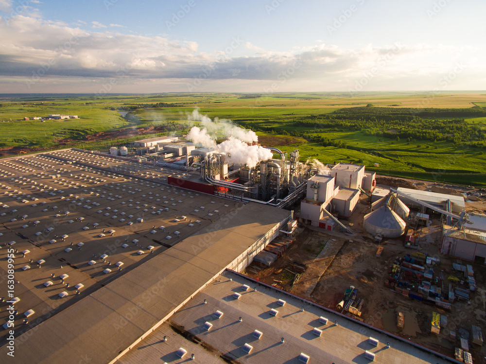 a huge concrete plant with pipes among the fields. aerial view