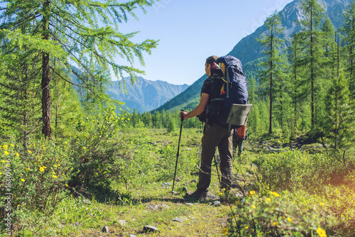 Healthy Active man with backpack hiking in beautiful mountain forest in the summer in the sun