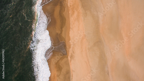 Aerial view of ocean sea waves on sandy beach at evening