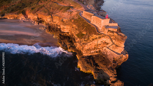 Aerial view of ocean and Nazare lighthouse at sunset, Portugal