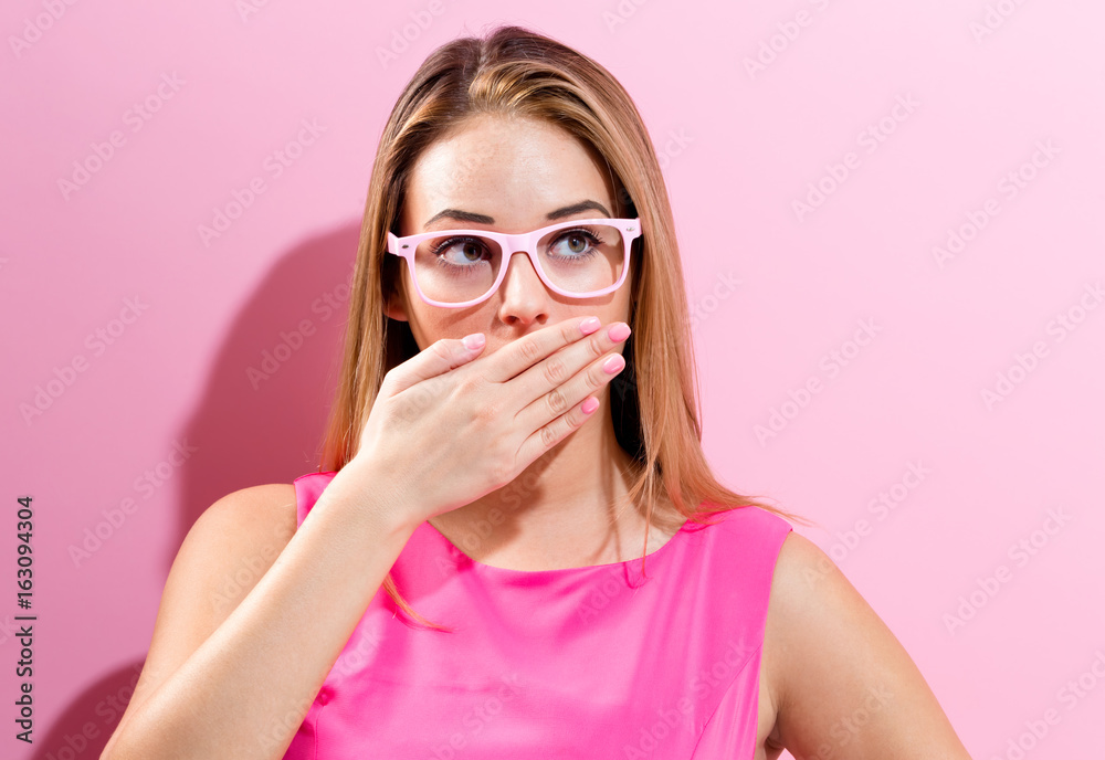 Young woman covering her mouth on a pink background Young woman covering her mouth on a pink background