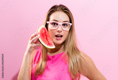Happy young woman holding watermelon on a pink background