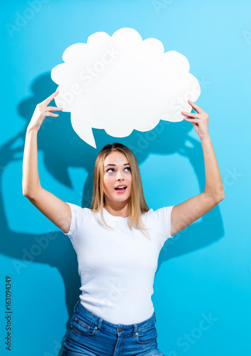 Young woman holding a speech bubble on a blue background