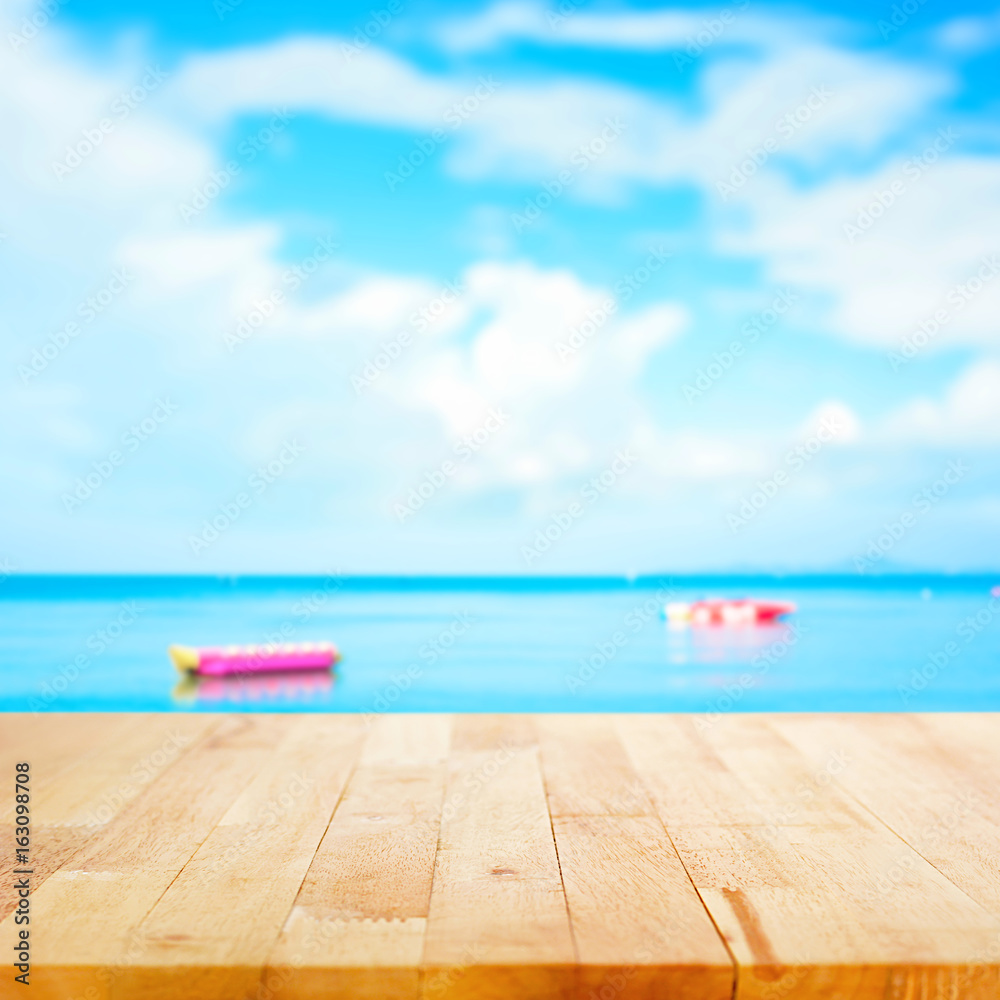 Fototapeta premium Wood table top on blur summer sky and sea with banana boats as background