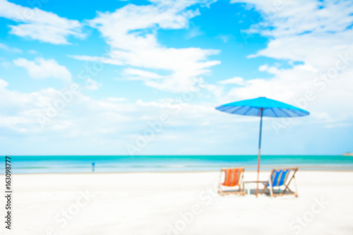Fototapeta Naklejka Na Ścianę i Meble -  Blurred image of beach chairs and parasol on white sand beach in summer blue sky background
