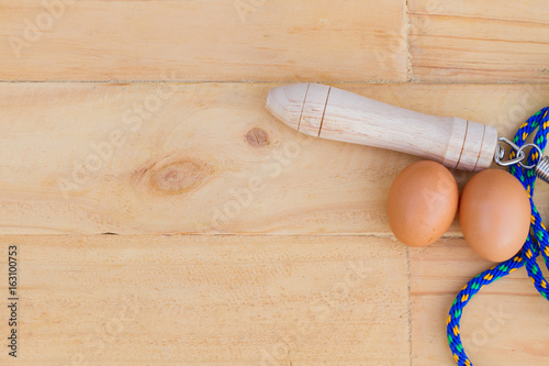 top view blue jump rope with two eggs on wooden bakcground, sex concept, copyspace for text