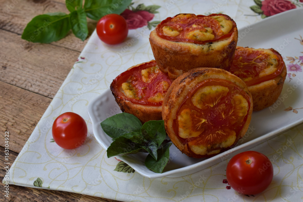 Salty snack. Homemade muffins with cheese, tomatoes and basil on wooden background. Savory pastry. Salty snack. Homemade muffins with cheese, tomatoes and basil on wooden background. Savory pastry.