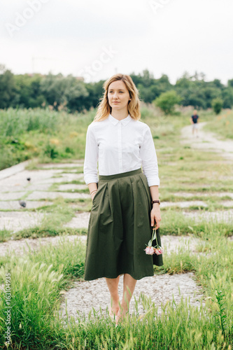 Beautiful woman holding flowers while standing outdoors