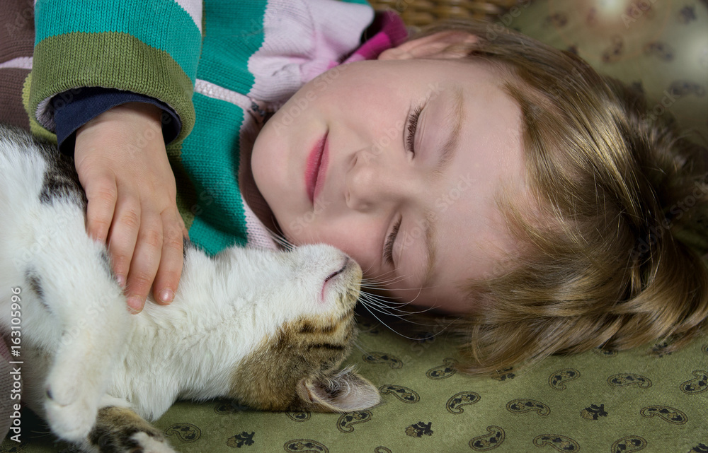 Little girl and young cat are sleeping.