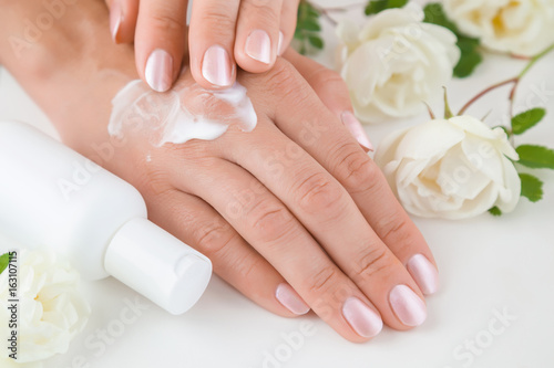 Hands moisturizing cream cares about woman s hands skin. Manicure beauty salon. Spring and summer gentle atmosphere with fresh and fragrant white roses on the table.