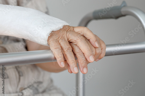 Senior woman with broken arm using the toilet with walker.