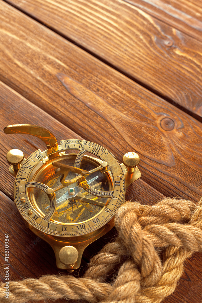 Fototapeta premium Compass and rope on wooden table. close up