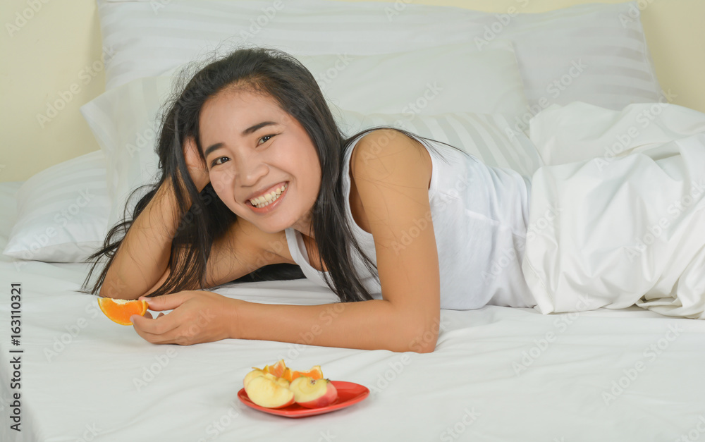 healthy  woman on white bed in a room and fruit