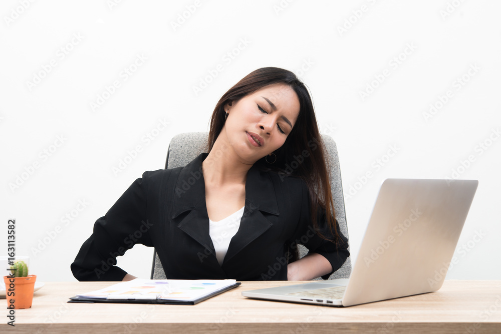 Young business woman looks stressful and tired sitting at workplace with laptop on the table isolated on white background Young business woman looks stressful and tired sitting at workplace with laptop on the table isolated on white background