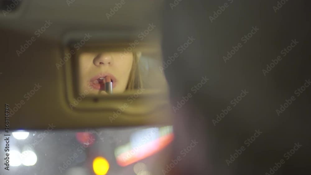 Young Woman Uses Car Mirror To Apply Lipstick For Night In The City Young Woman Uses Car Mirror To Apply Lipstick For Night In The City