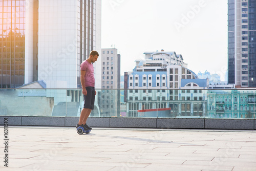 Man on hoverboard, city background. Young male outdoors.