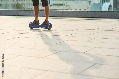Legs of man on gyroboard. Person riding blue hoverboard.