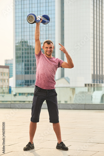 Smiling man with a hoverboard. Happy guy on urban background. Gadget sale with discounts.