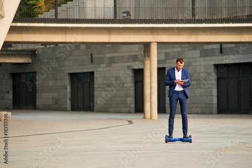 Businessman on gyroboard. Man holding tablet outdoor.