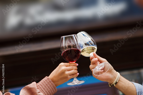 Two people clinking glasses with red and white wine