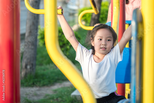 Happy asian baby child playing on playground , exercise equipment in the garden