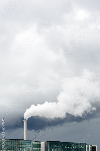 Industrial smoke emission from factory chimney under a stormy sky.
