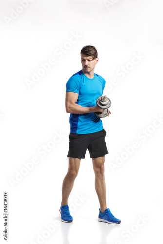 Fitness man holding dumbbell, working out, studio shot.