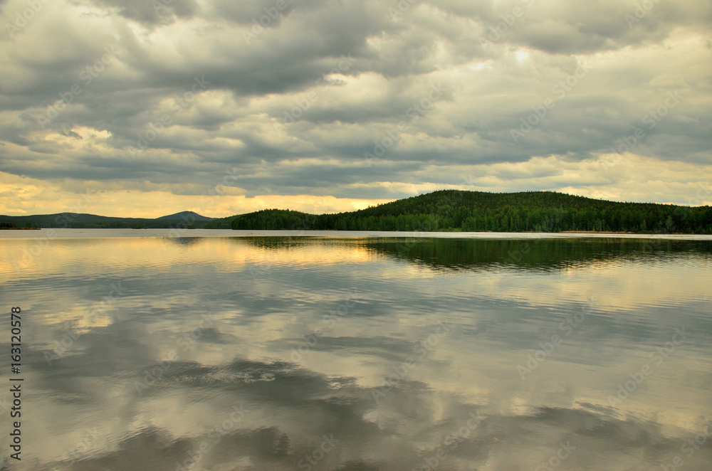 Fototapeta premium overcast on the lake and reflection of the clouds in the water
