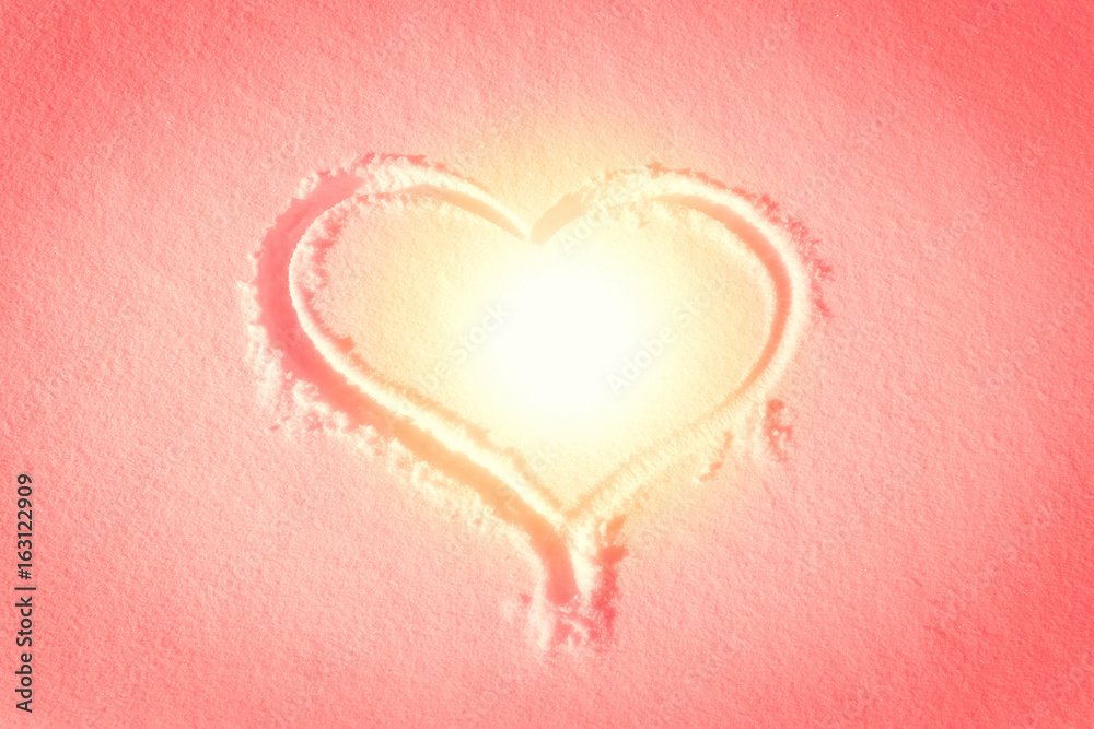 Heart shape drawn in the snow, warm sunset style colors