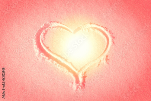 Heart shape drawn in the snow  warm sunset style colors