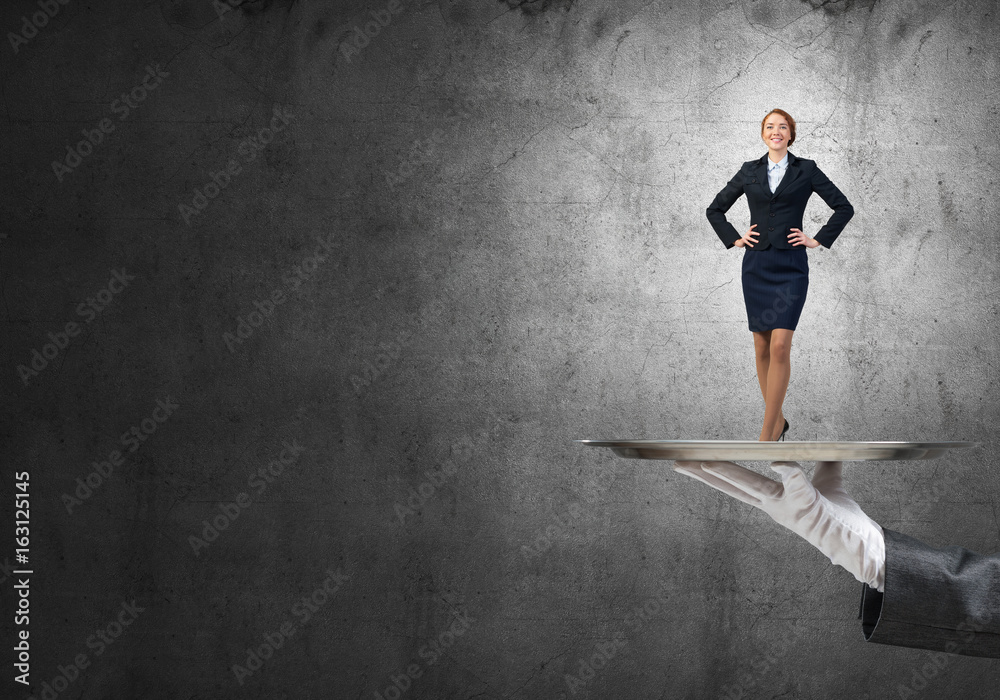 Confident elegant businesswoman presented on metal tray against concrete wall background Confident elegant businesswoman presented on metal tray against concrete wall background