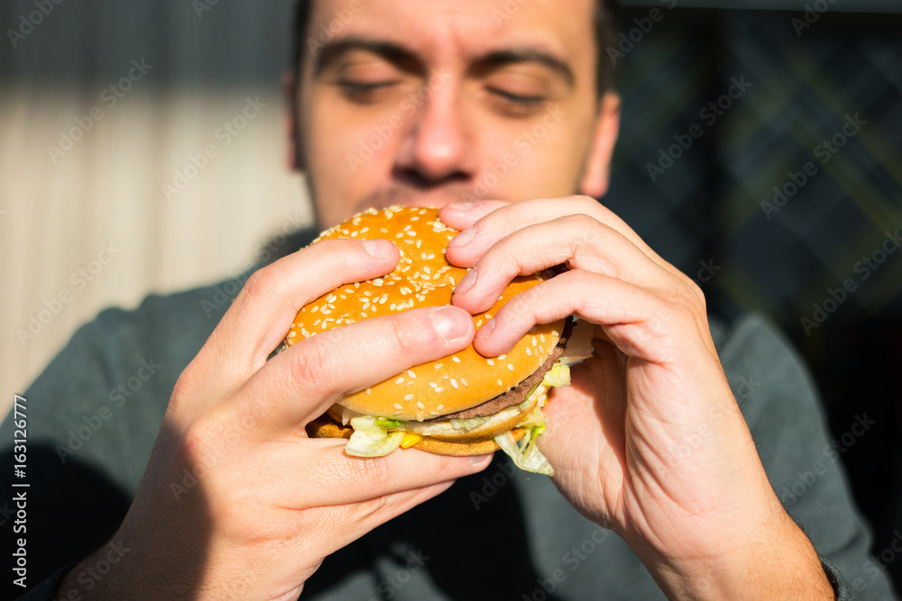 Man eating an hamburger in a fast food Man eating an hamburger in a fast food